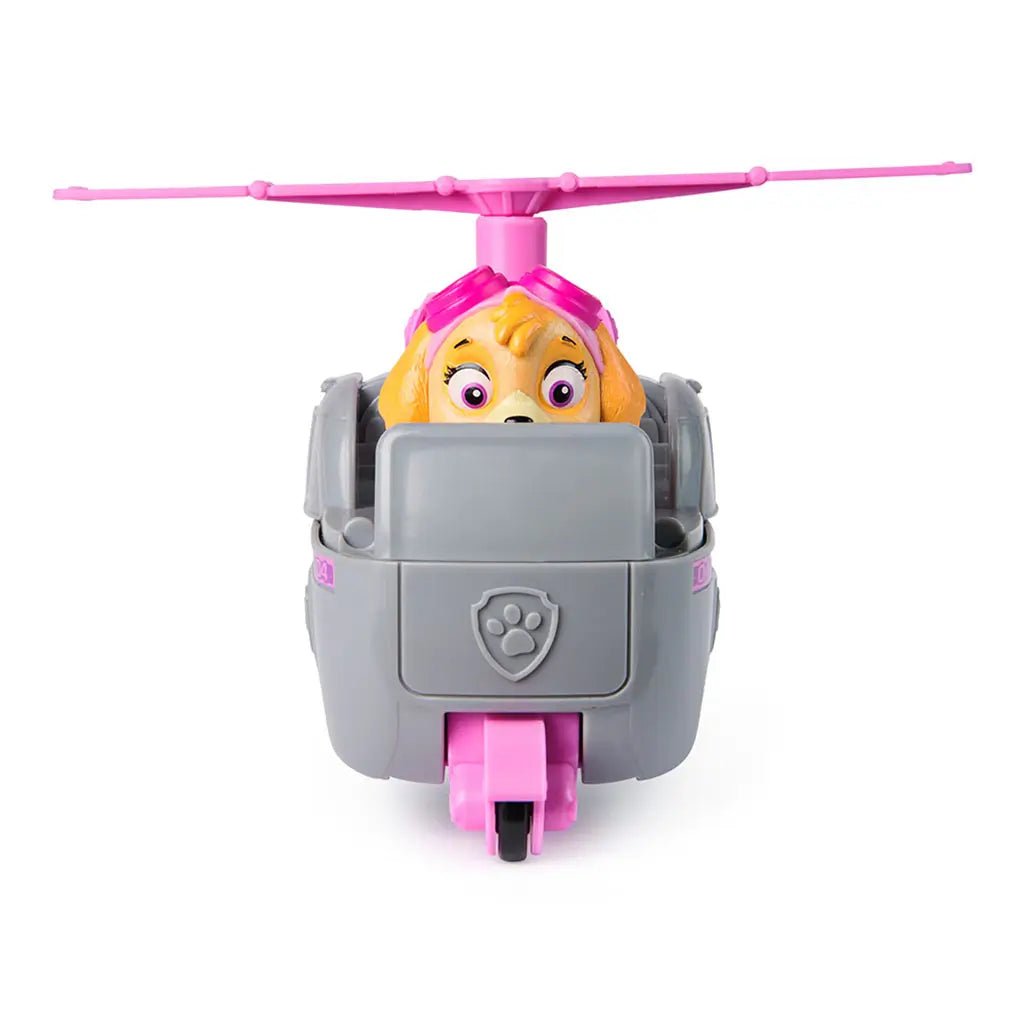 Front view of Paw Patrol Skye helicopter toy, gray and pink cockpit with paw badge emblem, large rotor blades above, and Skye pup in pink goggles visible inside.