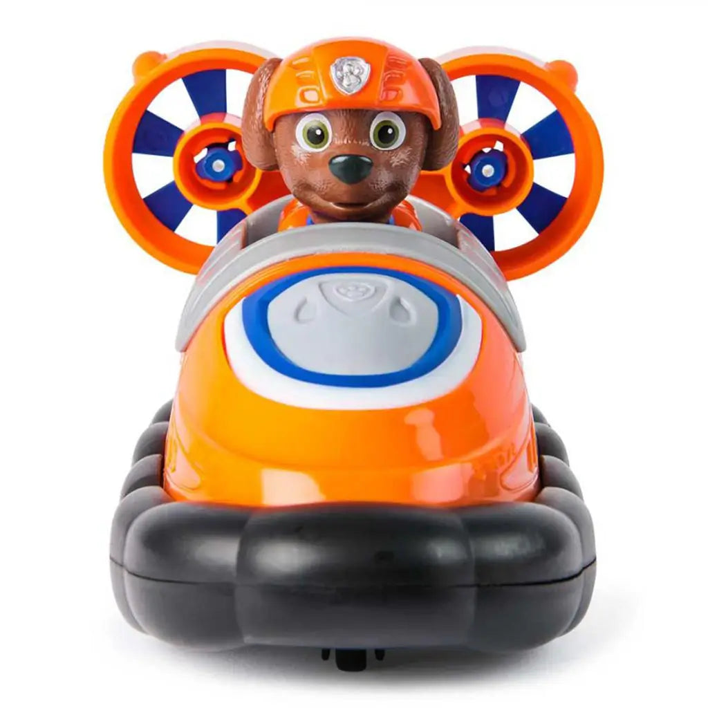 Front view of Paw Patrol Zuma hovercraft toy, with orange and gray cockpit, black float base, and Zuma pup character visible behind twin orange propellers.