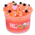 Peach-orange icee slime with a textured, slushy appearance, topped with a pink peach charm, black boba pearls, star confetti, and glitter, packaged in a jar labeled Peach Boba Slushie Icee Slime.