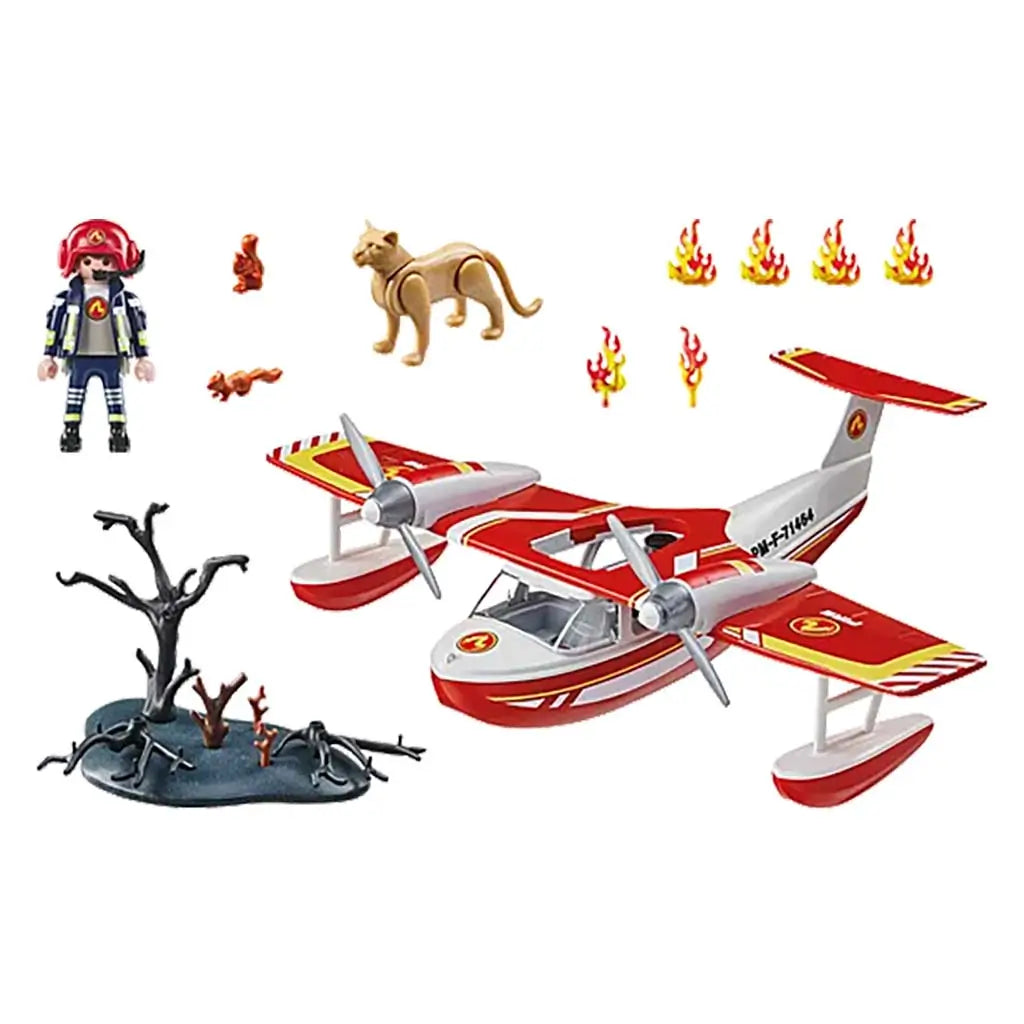 Playmobil firefighting seaplane set with bright red and white aircraft, small flame pieces, firefighter figure, animal figure and charred tree base arranged neatly against a clean white backdrop.