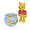 Playmobil Winnie the Pooh toy set with smooth yellow plastic figure, bright red shirt, rounded blue honey pot and dripping honey detail arranged against a clean white background for preschool play.