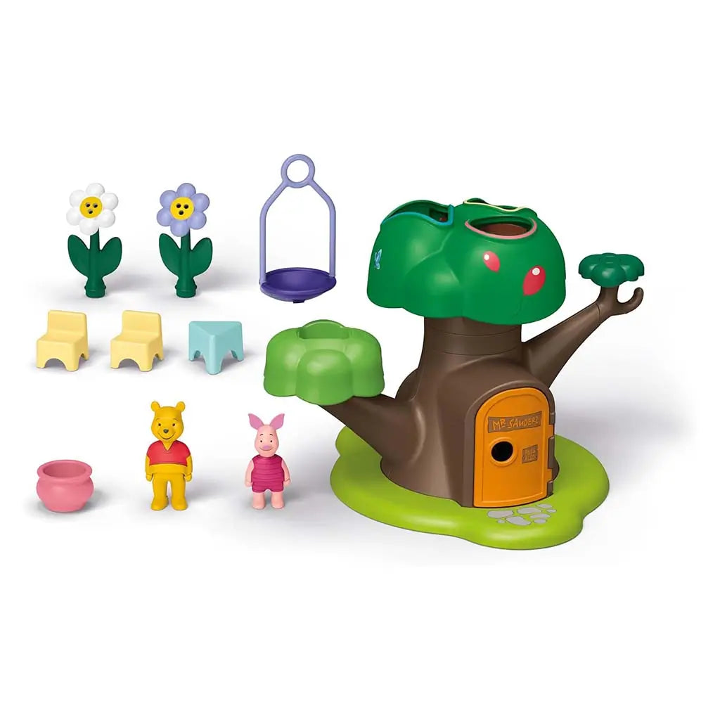 Disney Playmobil Junior Winnie the Pooh set showing colorful plastic tree house, rounded shape-sorting blocks, two smiling flowers, swing piece, and Pooh and Piglet figures arranged neatly on a white surface.