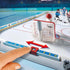 Playmobil NHL tabletop rink close‑up shows white goal net, sliding blue score tracker, smooth ice surface markings, and player figures positioned in a brightly lit stadium-style environment.