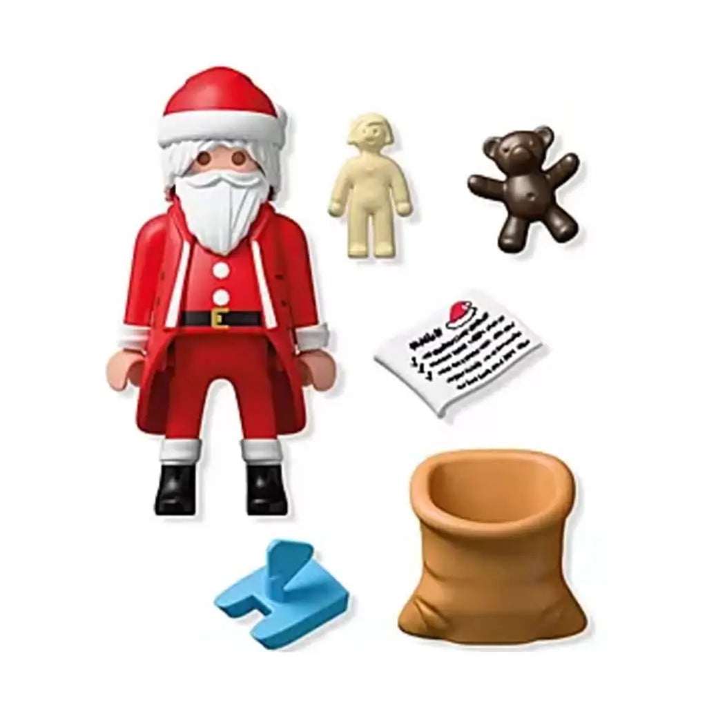 Playmobil Santa set shows red-suited figure with white beard, toy sack, teddy bear, doll, blue stand and printed wishlist arranged neatly for imaginative holiday play scenes.
