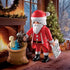 Playmobil Santa scene places red-suited figure by warm fireplace and glowing tree, holding teddy bear above stuffed toy sack in cozy winter room filled with festive décor.