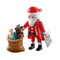 Playmobil Santa figure in red suit stands beside brown toy sack holding small teddy bear and doll, with white wishlist in hand set against clean background for festive play.