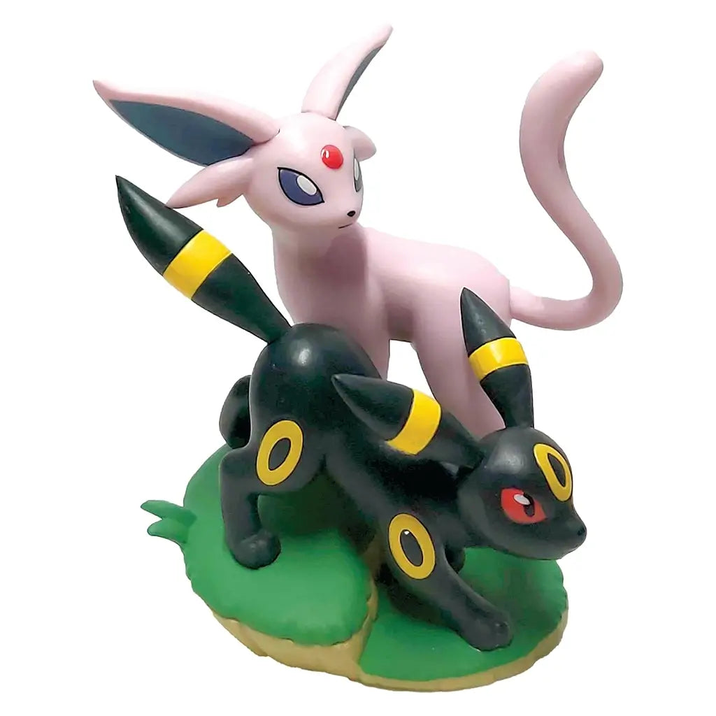 Pokémon TCG Espeon and Umbreon collectible figure in pink and black molded plastic with yellow ring accents, posed together on a green base against a clean white backdrop.