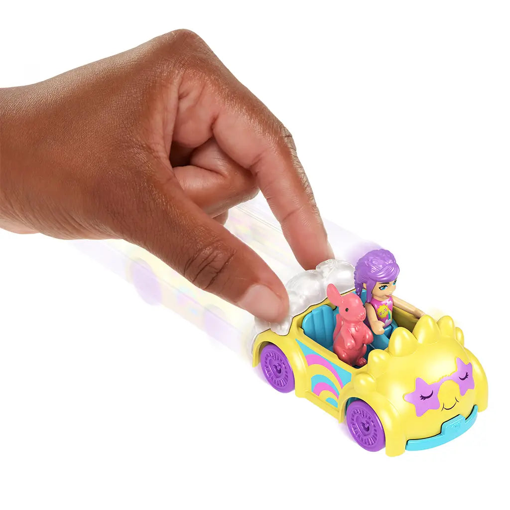 Hand pushing Polly Pocket yellow star car with smiling face and cloud accents, showing seated Polly doll with purple hair and pink dog figure inside.