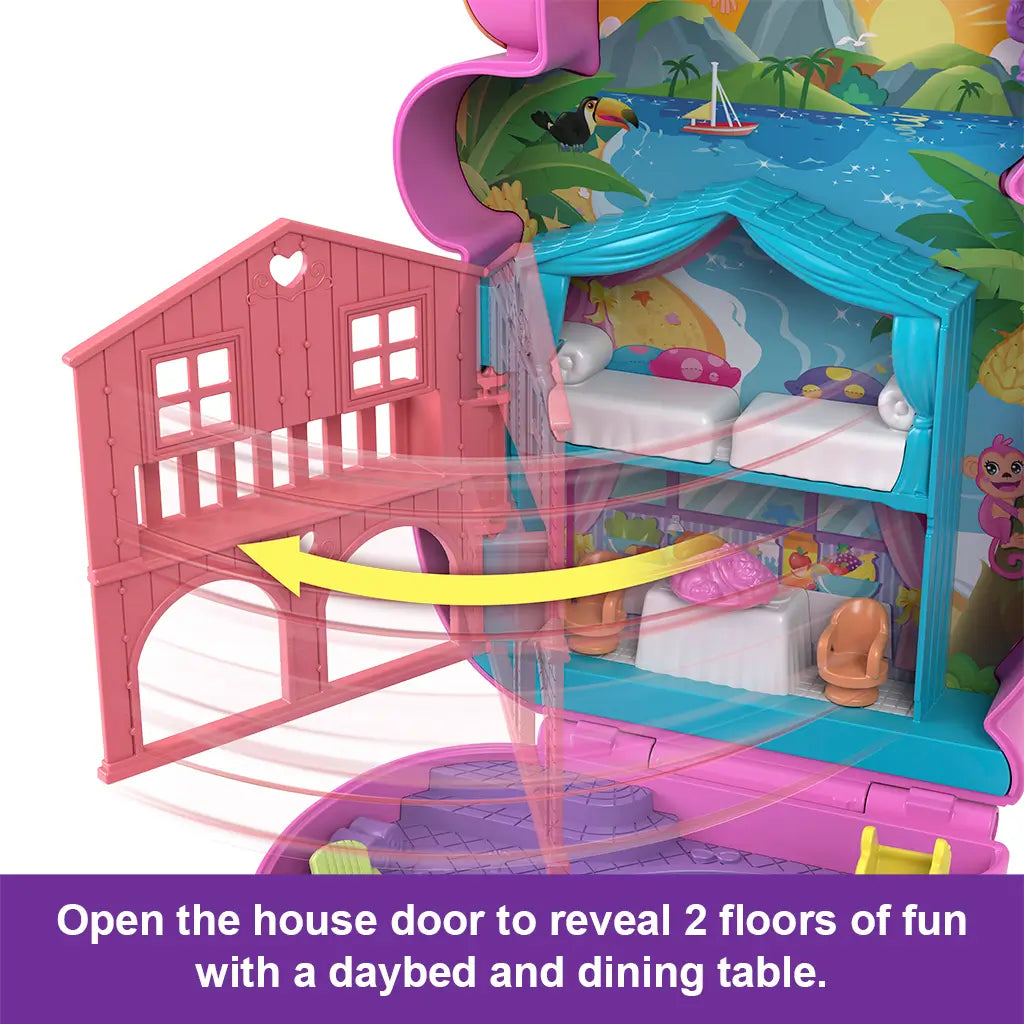 Close-up of Polly Pocket Momma Monkey playset house with two floors revealed, showing a dining table, chairs, and daybed beneath a beach and jungle-themed backdrop.
