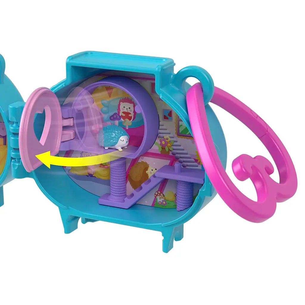 Inside Polly Pocket Pet Connects hedgehog locket playset showing a colorful pet playroom with purple running wheel, tiny hedgehog figure, and playful illustrated background.