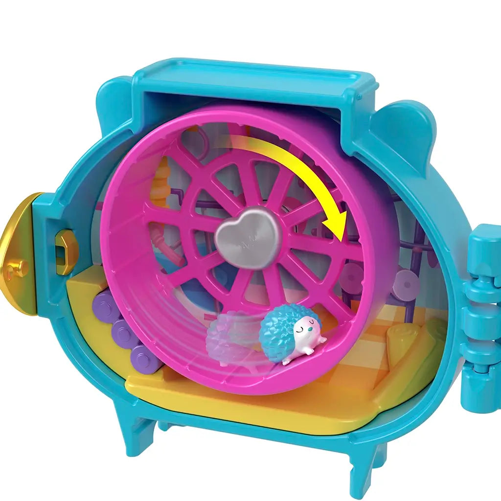 Close-up of Polly Pocket Pet Connects hedgehog locket interior showing bright pink hamster wheel with tiny blue hedgehog toy inside, set against colorful playhouse backdrop.
