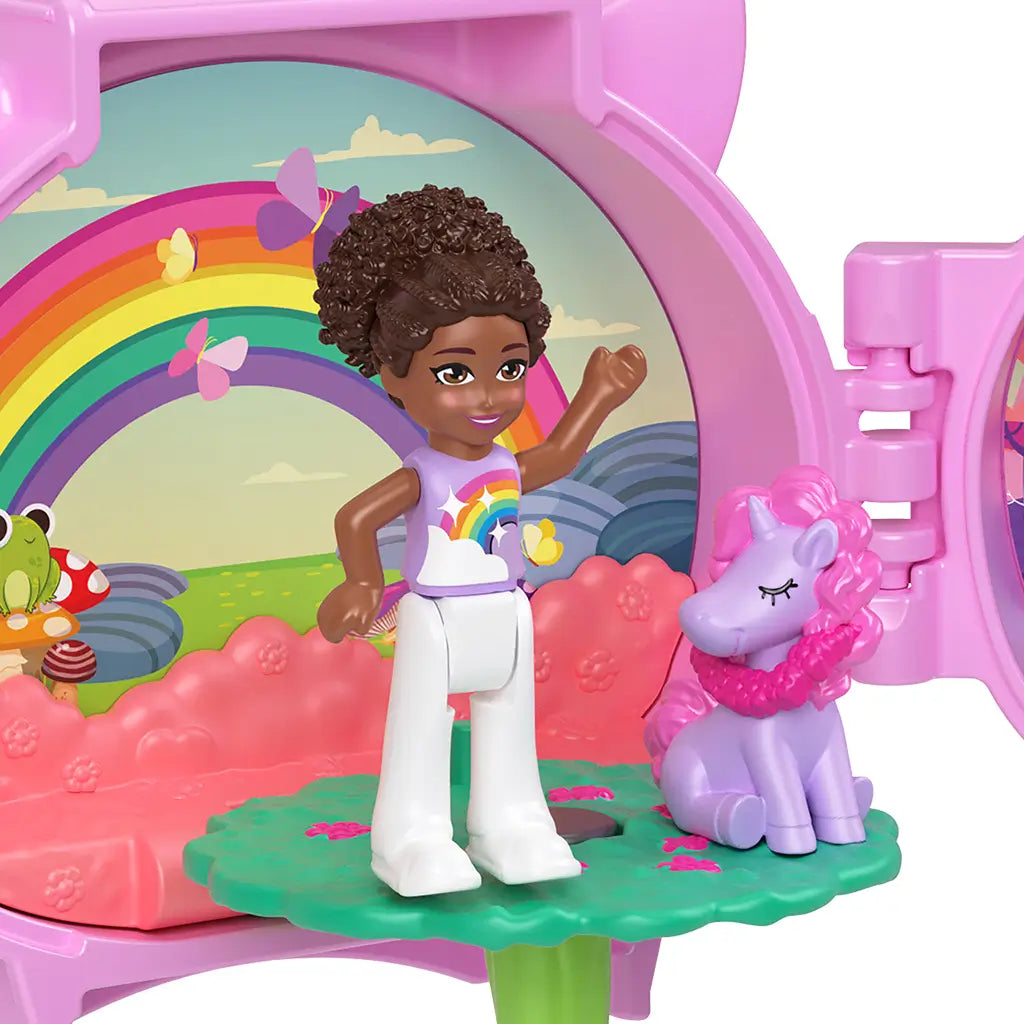 Polly Pocket doll in rainbow shirt standing beside purple unicorn figure inside open locket playset, with rainbow backdrop, pink seating area, and butterfly accents.