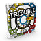 Pop-O-Matic Trouble board game box displaying a white cardboard package with bold black outlines, red, blue, yellow, and green graphics, circular track artwork, Hasbro branding, and a Try Me callout on the front panel.