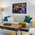 Completed Disney Villainous Ravensburger puzzle framed on a wall above a modern white sofa with teal pillows, glowing with vivid Ursula-themed artwork in gold-trimmed frames.