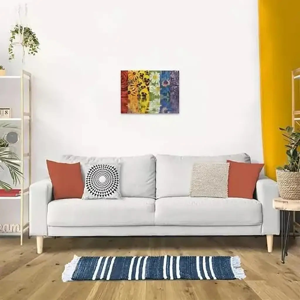 Modern living room with a white sofa, orange pillows, and a striped rug features the completed Ravensburger Floral Reflections puzzle framed on the wall.