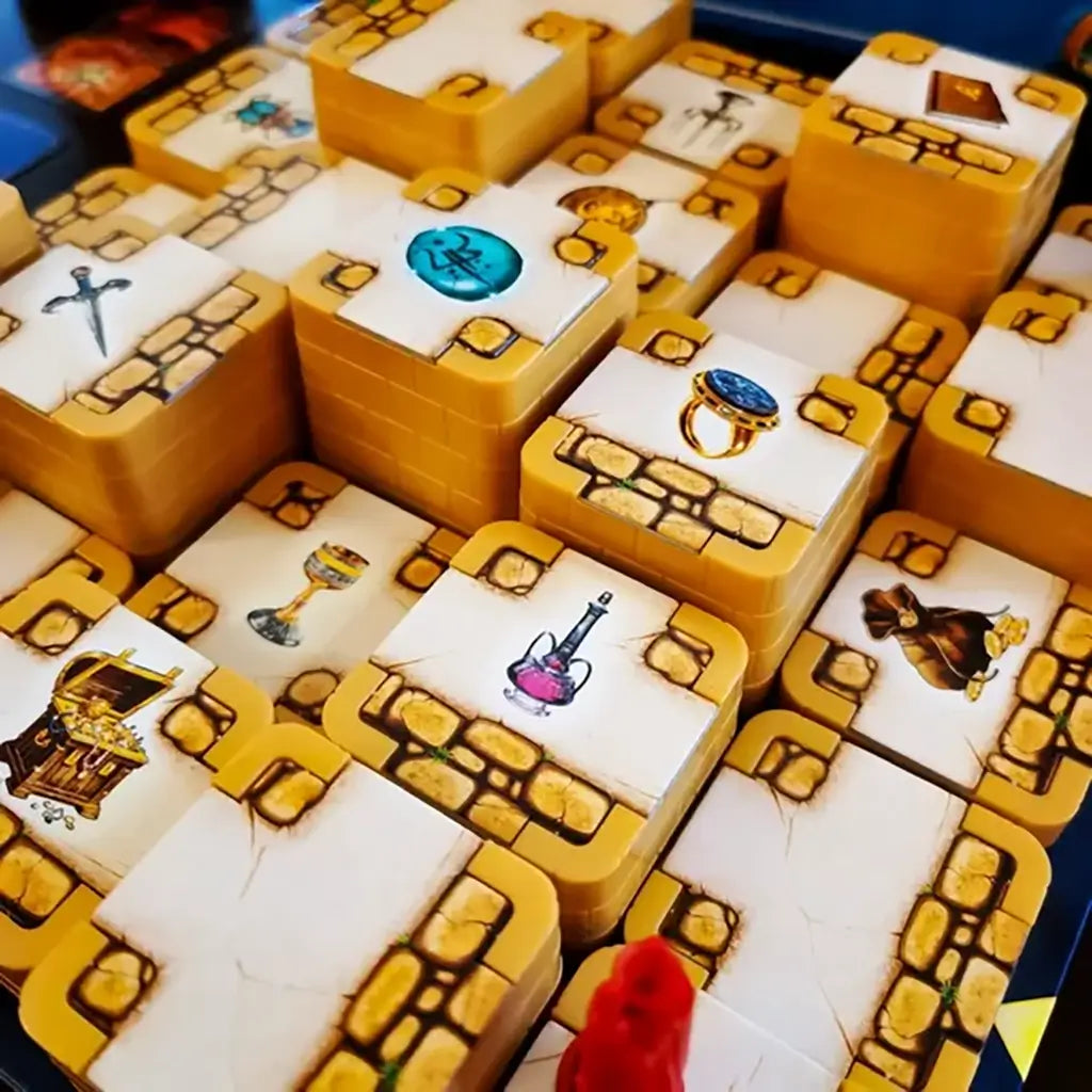 Close-up of Ravensburger 3D Labyrinth maze blocks featuring printed treasures like jewels, sword, potion, and chest, highlighting detailed artwork on stacked golden tiles.