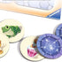 Ravensburger Labyrinth Junior board game tokens with colorful round pieces showing a green frog, purple spider web, and pink potion bottle against a stone maze design.