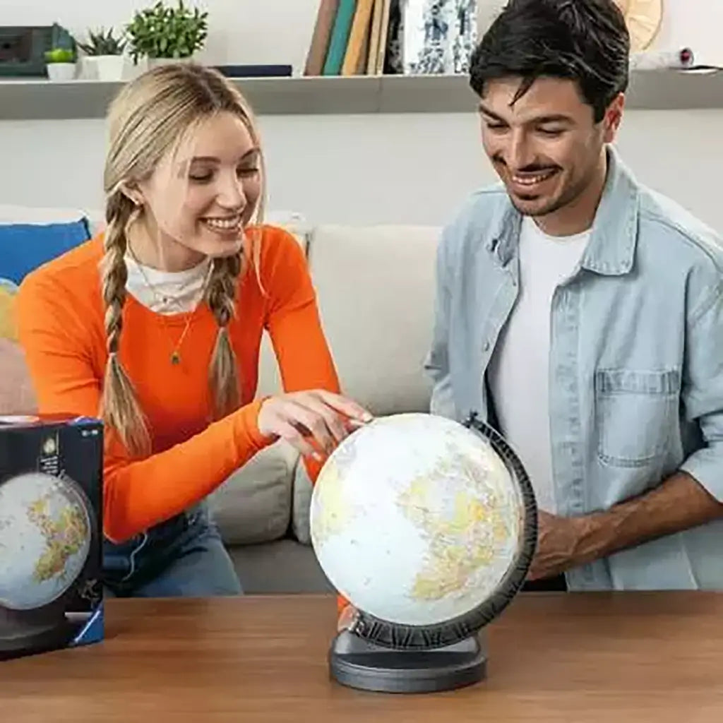 Smiling man and woman assemble a Ravensburger 3D Puzzle Globe on a wooden table, highlighting its bright world map pieces, sturdy gray base, and engaging hands-on fun.