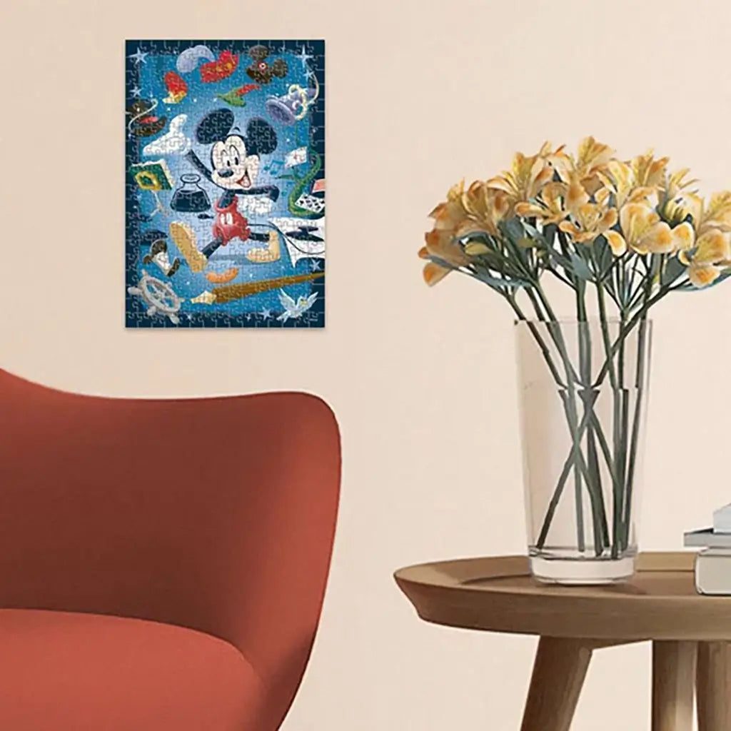 Completed Ravensburger Disney Mickey Mouse 300 piece puzzle framed on wall above wooden side table with glass vase of yellow flowers, next to red modern armchair.