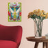 Completed Ravensburger Disney Tinker Bell 300 piece puzzle framed on wall above wooden side table with vase of yellow flowers, red chair in modern home setting.