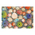 Completed Ravensburger puzzle image showing an assortment of colorful seashells, sea urchins, and beach pebbles arranged naturally on sandy shore background.