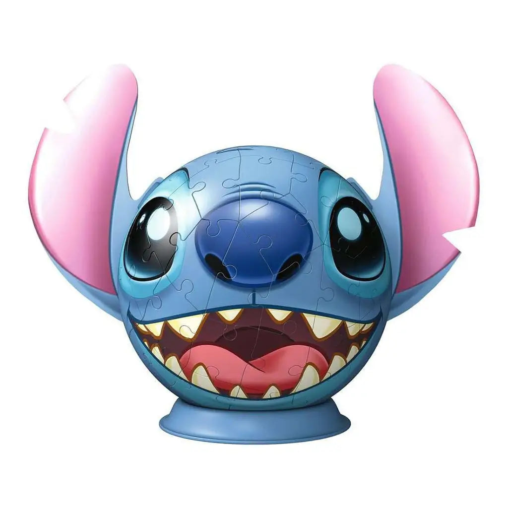 Close-up of completed Ravensburger 3D puzzle featuring Stitch’s round blue head with pink ears, wide grin, sharp teeth, and glossy cartoon eyes on a sturdy blue stand.