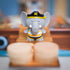 Close-up of a gray elephant figurine in a pirate hat and striped shirt standing on a cardboard plank in the board game Stomp the Plank.