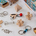 Set of wooden, metal, and rope brain teaser puzzles, including geometric blocks, rings, and spring pieces, arranged beside open matchbox-style puzzle boxes.