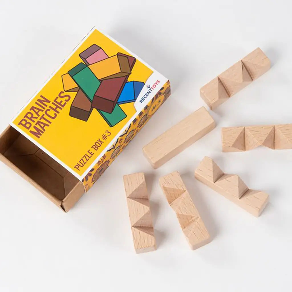 Wooden block puzzle with rectangular pieces featuring triangular ridges, displayed beside Brain Matches Puzzle Box #3 packaging with colorful illustration.