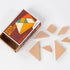Wooden tangram puzzle pieces shaped as triangles and squares spread out beside Brain Matches Puzzle Box #4 packaging with geometric design illustration.