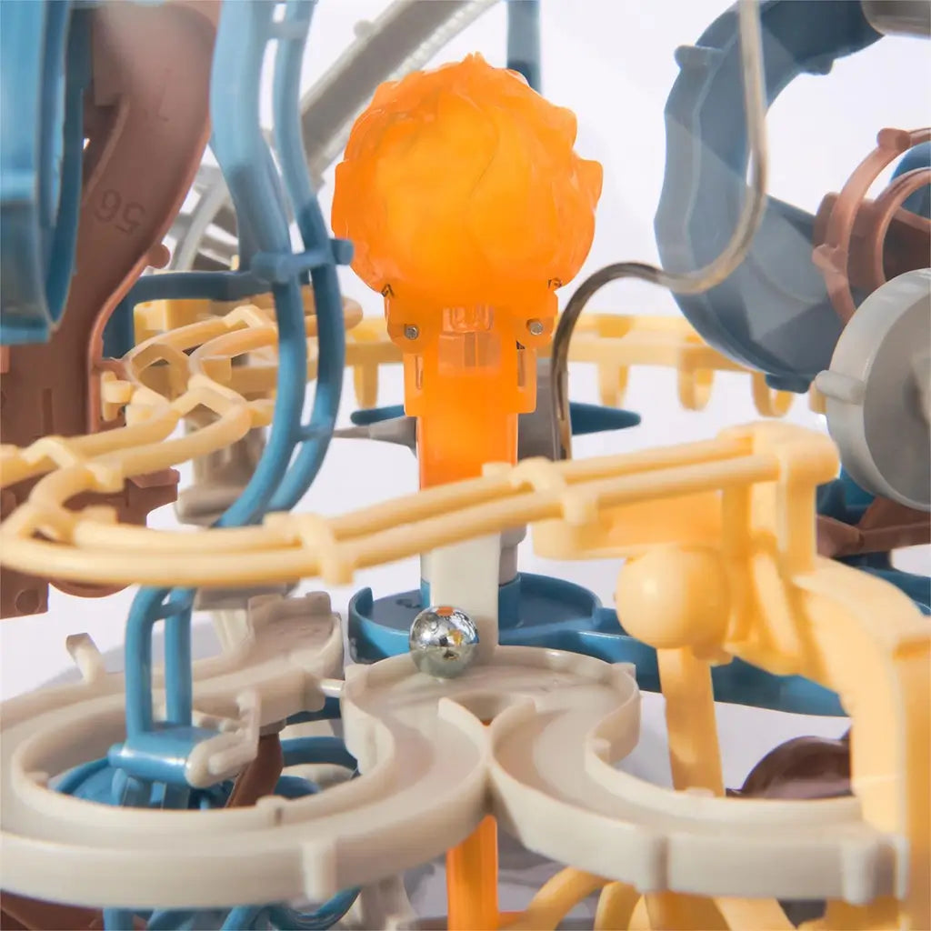 Star Wars Mandalorian gravity maze close-up shows blue, tan, and gray plastic tracks surrounding a bright orange center tower with a silver metal ball, highlighting intricate 3D obstacle details.