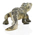 Schleich baby alligator figurine displaying olive green and tan textured plastic, rear angled crawling stance, segmented tail and raised scale ridges, designed as a durable wildlife toy against a plain white background.
