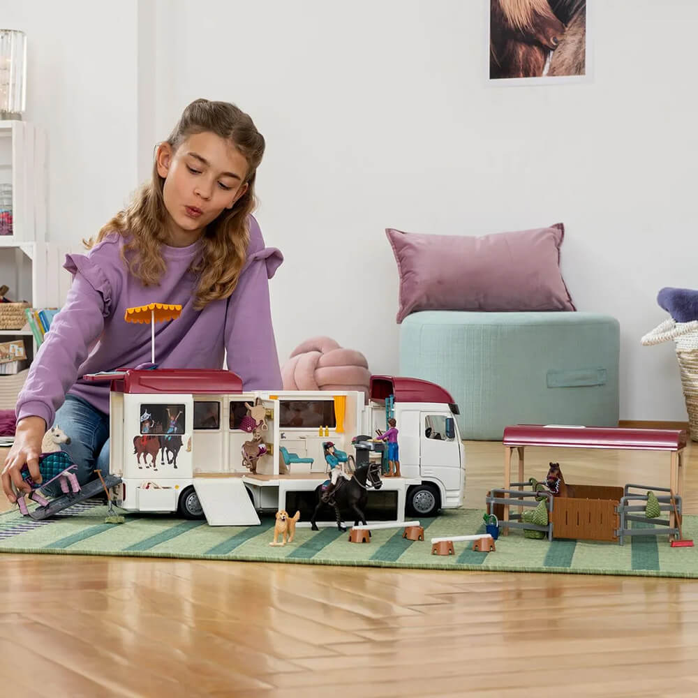 Girl playing with Schleich Horse Club Horse Transporter Set on the floor