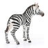 Schleich zebra foal figurine displaying white and black striped textured plastic, rear angled standing pose, sculpted tail and legs, designed as a durable wildlife toy against a clean white background.
