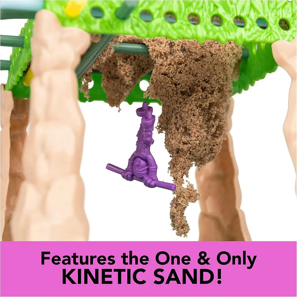 Sink N’ Sand game close-up with brown kinetic sand falling between sticks as a purple explorer figure dangles below, captioned “Features the one & only Kinetic Sand!”