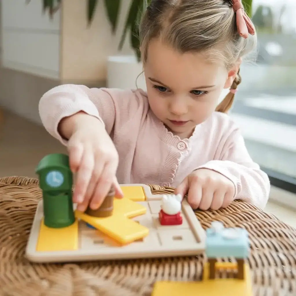 Focused girl playing Smart Games Hide & Goat Seek puzzle at home, moving a brown barrel piece on the yellow-tiled board with visible goat, wolf, and table figurines nearby.