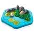 Close-up of Smart Games Treasure Island puzzle board showing a sailboat on blue water, green forests, gray mountains, and a beige temple hidden among the landscape pieces.