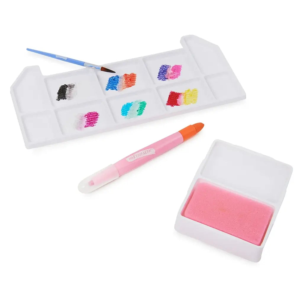 Inkfluencer Click N’ Blend watercolor set tools with pink stylus pen, white palette showing sample colors, paintbrush, and pink sponge block for blending effects.