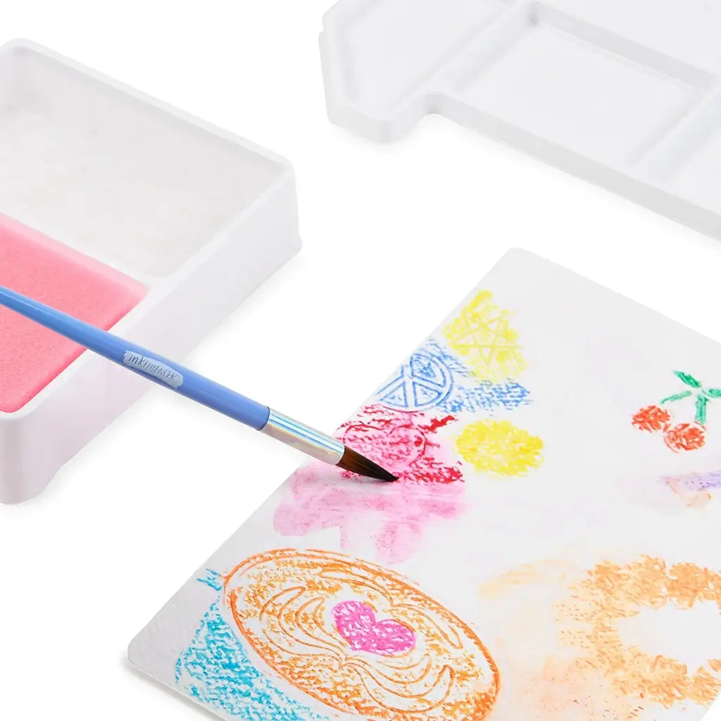 Close-up of watercolor brush blending pink and yellow pigments on Inkfluencer design card, creating smooth painted textures alongside other colorful drawings.