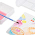 Close-up of watercolor brush blending pink and yellow pigments on Inkfluencer design card, creating smooth painted textures alongside other colorful drawings.