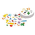 Spot It! Classic card game features white round cards with colorful symbols including animals, anchors, cactus, pencil, clock, turtle, and keys, spread in overlapping stacks.