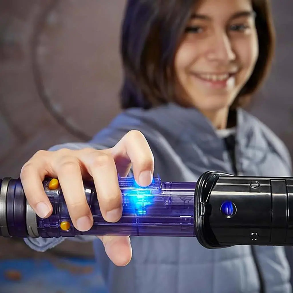Child activating Star Wars Lightsaber Forge toy by pressing illuminated blue button on the translucent purple hilt, demonstrating lights and sounds during energetic imaginative Star Wars play.