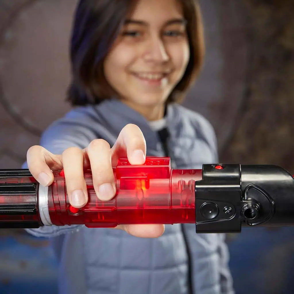 Close-up of child pressing glowing red button on translucent red hilt of the Star Wars Lightsaber Forge Darth Vader lightsaber, showing lit core effects and detailed black emitter housing.