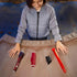Child arranging Star Wars Lightsaber Forge Darth Vader components on a curved wooden table, including red hilt pieces, black connector, and red blade, preparing the customizable lightsaber for play.