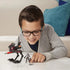 Smiling child wearing glasses and a gray hoodie playing with a Star Wars Mission Fleet Tech Bad Batch AT-RT Ambush toy set on a white table, posing the figure beside the walker vehicle.