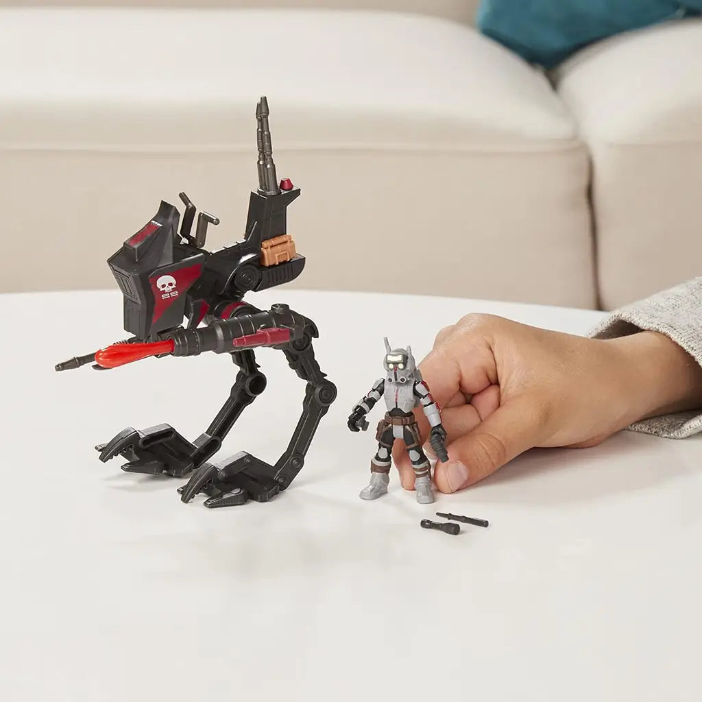 Poseable Star Wars Mission Fleet Tech Bad Batch AT-RT Ambush toy featuring black and red walker with articulated legs and red projectile, displayed with Tech figure and accessories on a white table.