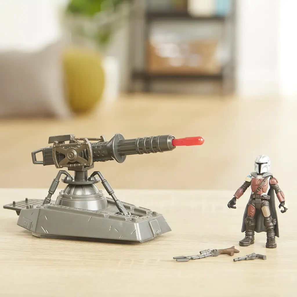 Star Wars Mission Fleet Mandalorian hover E-Web cannon toy displayed on a tabletop beside the Mandalorian action figure and blaster accessories, set against a softly lit home background.