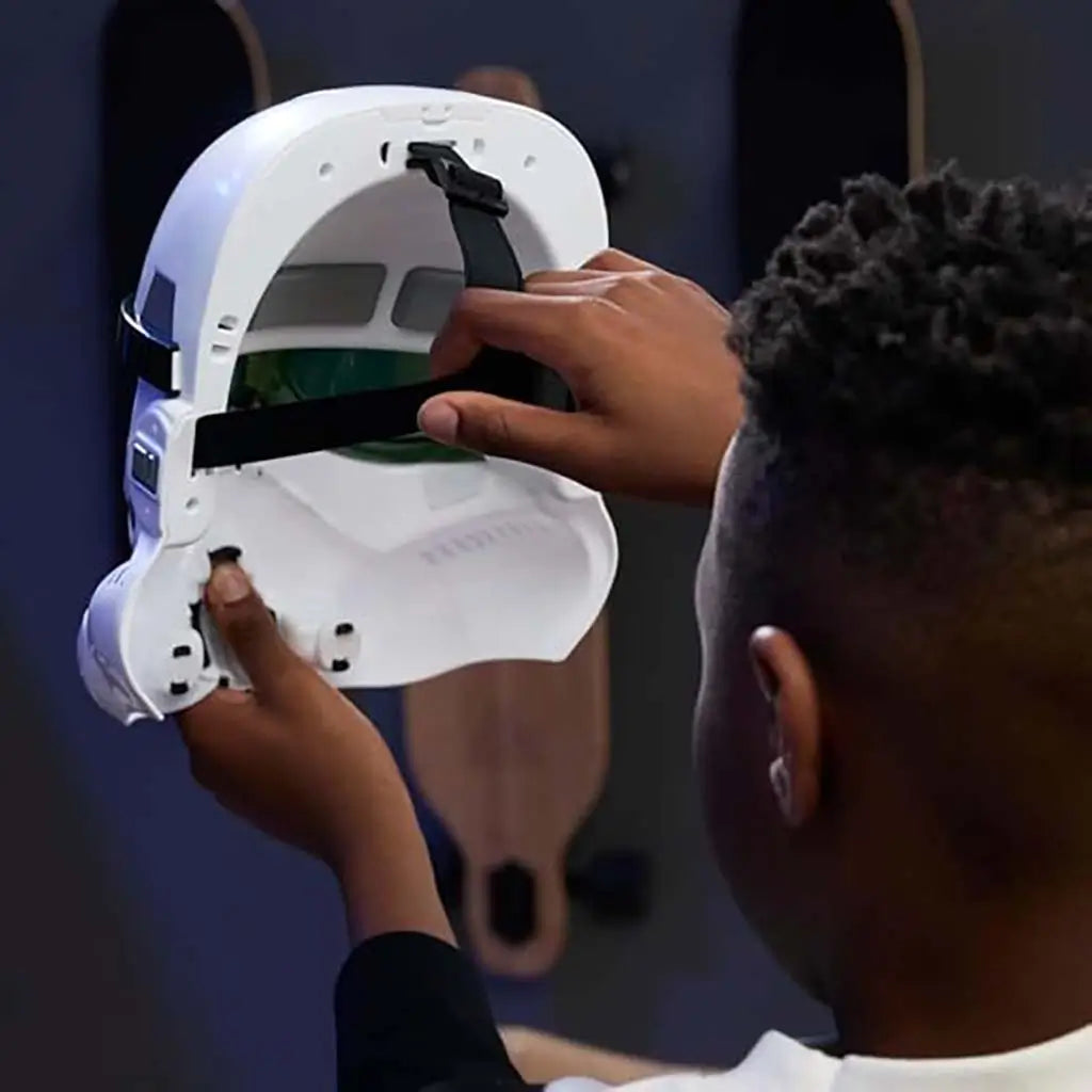 Star Wars Stormtrooper electronic helmet held open by child revealing interior straps and green-tinted lenses, displaying lightweight molded plastic design during at-home playtime.