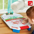 Super Mario air hockey tabletop game in white plastic with red and green details, shown on a wooden table with a child playing, featuring Mario and Luigi graphics.
