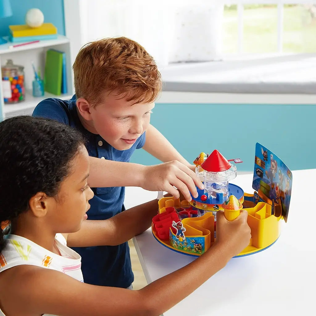 Two children focus on Super Mario Castle Land maze game, using bright mushroom controllers to move the ball through castle traps decorated with Mario, Luigi, and Nintendo characters.